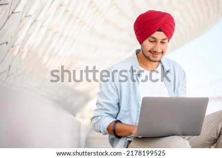 Indian freelancer man in traditional turban sitting outdoors with laptop, developer working on the distance, hindu guy enjoys remote work, male student studying online, e-learning concept