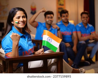 Indian friends dressed in Indian cricket team jerseys - faces painted with three colors of the Indian flag, a cheerful gesture. Excited cricket fans sitting at home watching a game on TV - Powered by Shutterstock