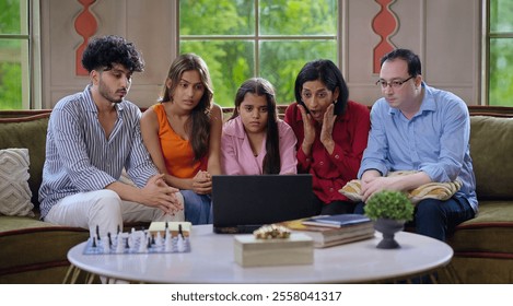 Indian frightened family group use laptop watch scary horror scene in  movie feels fear closed eyes spend time indoor house. Young adult girl boy sitting on cozy sofa couch look thriller show together - Powered by Shutterstock