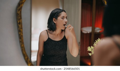 Indian gen x old aged smiling woman reflected look bathroom mirror hold toothbrush brushing healthy white teeth clean mouth with toothpaste do morning day dental care daily routine indoor home - Powered by Shutterstock