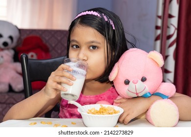 An Indian Girl Child Drinking Milk With Cereals Looking At Camera