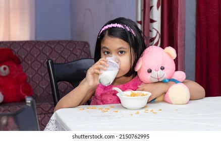 An Indian Girl Child Drinking Milk With Cereals Looking At Camera