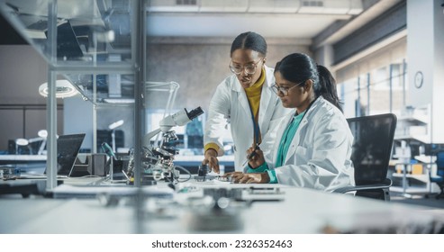 Indian Girl Having a Conversation with a Mentor in a Laboratory, While Working on a Circuit Board for a Project. Young Scholar Talking with a Scientist About Changing the CPU Memory Characteristics - Powered by Shutterstock