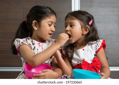 Indian Girls Sharing Food, Murukku With Each Other. Asian Sibling Or Children Living Lifestyle At Home.