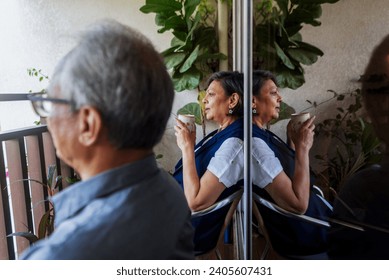 An Indian grandmother takes a sip of her freshly made filter coffee while sitting in the balcony with her husband one afternoon at their home in Mumbai, India. - Powered by Shutterstock