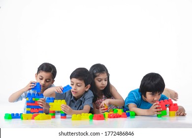 Indian group of preschool children are playing together with colorful plastic blocks and are building towers.