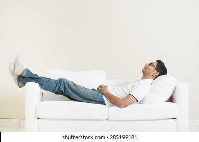 Indian guy daydreaming and rest at home. Asian man relaxed and sleep on sofa indoor. Handsome male model. - Powered by Shutterstock