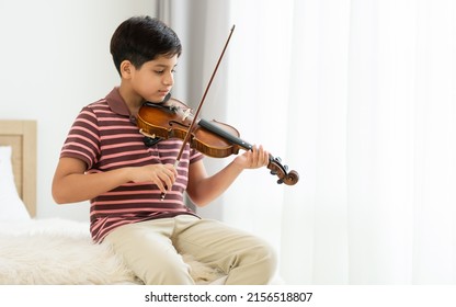 Indian handsome teenage boy, playing, practicing violin musical instrument with happiness in bedroom at cozy home in leisure time, smiling, having copy space. Education, Lifestyle, Creativity Concept - Shutterstock ID 2156518807