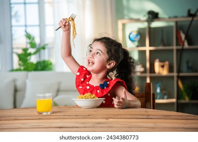 Indian happy little girl eat pasta spaghetti or noodles in a bowl at home - Powered by Shutterstock