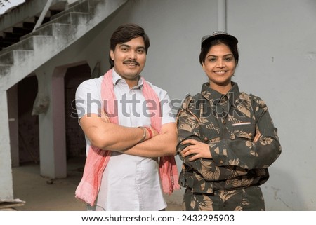 Indian happy rural male with her Army woman wife standing at home.
