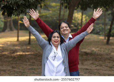 Indian happy senior couple spreading hands at park. old couple looking at the sky while spending time together, relationship and people concept. Senior Living Retirement and Pension Plans Concept - Powered by Shutterstock