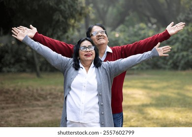 Indian happy senior couple spreading hands at park. old couple looking at the sky while spending time together, relationship and people concept. Senior Living Retirement and Pension Plans Concept - Powered by Shutterstock