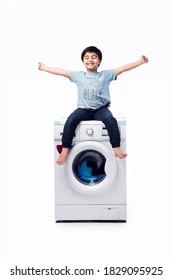Indian happy Small boy posing with Washing Machine or Dishwasher against white background