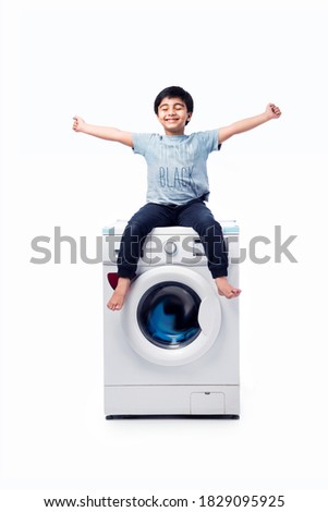 Indian happy Small boy posing with Washing Machine or Dishwasher against white background