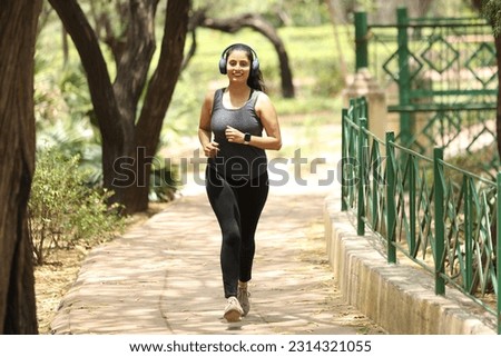 Indian happy women doing joking running and walking in garden ramp with headphone listening music feeling good