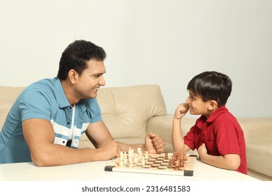 Indian happy Young father playing chess game with son at home - Powered by Shutterstock