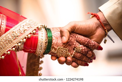 Indian Hindu Couple holding each other hands during their marriage symbolising love and affection. Hands of bride is decorated beautifully by indian mehndi art alongwith jewellery and colorful bangles - Shutterstock ID 1224274198