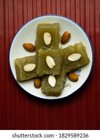 Indian Homemade Dessert Wheat Halwa Garnished With Almond On A Colorful Background