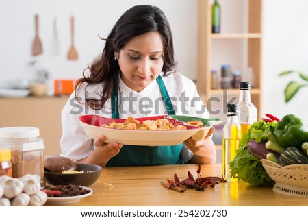 Indian housewife looking at the plate with appetizers in her hands