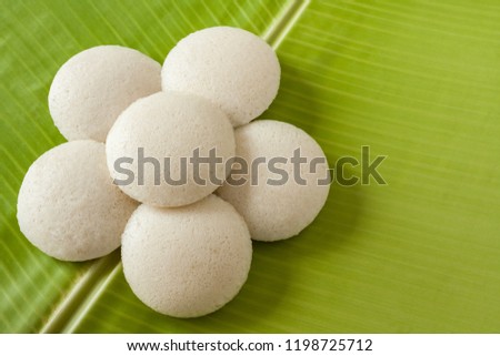 Indian idly served as a flower - Fresh steamed Indian Idly (Idli / rice cake) arranged decoratively as a flower on traditional banana leaf. Natural light used.
