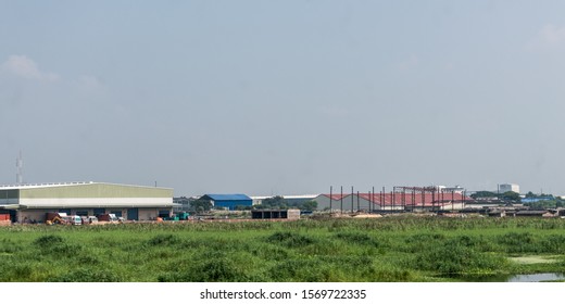 Indian Industrial Area Landscape. Industry Surrounded By Rural Agricultural Field And Green Summer Meadow. A Beautiful Non-urban Scenic Environment Of Rural Countryside Of India, South Asia Pacific.