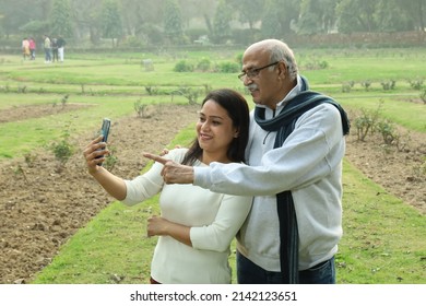 Indian Joyful Grand Father Looking Into The Mobile With Her Grand Daughter. They Both Look Happy And Cheerful.