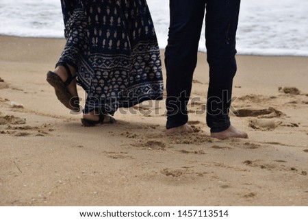 Indian kids and adult playing feet or foot on the beach sand and sea water  