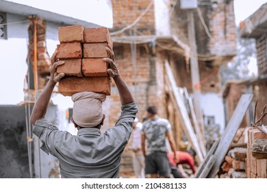 Indian Labour carries pile of bricks on his head 