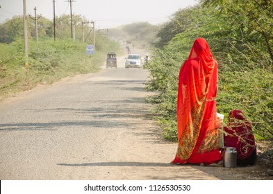 Indian Lady In Red Traditional Saree Waiting For A Bus On Road In Indian Village