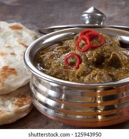 Indian Lamb Korma Curry In Traditional Copper Bowl, With Naan Bread.