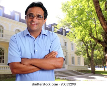 Indian Latin Man As Hotel Owner Or Real Estate Businessman Smiling In Front Of House Facade