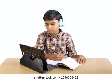 Indian little boy using digital tablet while attending the online classes at home	
