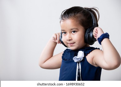 Indian Little Girl Listing Music On  Wire Less Headphone With Hands On Ear.
