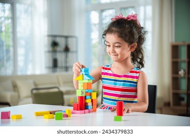 Indian little girl playing with wooden blocks toys on the table at home - Powered by Shutterstock