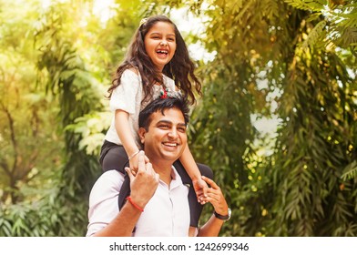 Indian little girl sitting on her fathers shoulders - Powered by Shutterstock