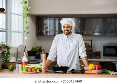 Indian male chef standing at home kitchen in relaxed pose and smiling - Powered by Shutterstock