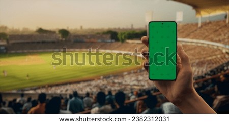 Indian male fan using phone during cricket game on a stadium, making bet. Online bookmaker, making bets on the internet