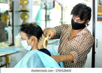 An Indian Male Hair Dresser Cutting Hair In His Beauty Saloon With Proper Safety Measures For Covid-19.Cutting Hair Of A Man In Mask. Hair Care During Covid-19.Beauty Saloon Opens After Lock Down.