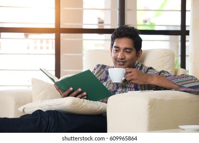 Indian Male Reading Book On Sofa