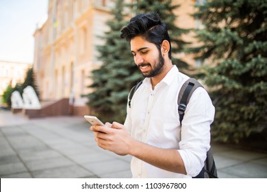 Indian male student texting on smartphone in the street