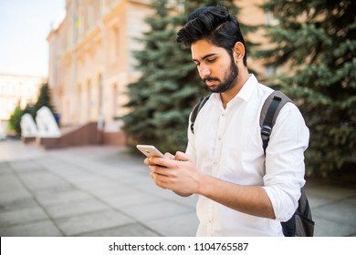 Indian Male Student Texting On Smartphone In The Street