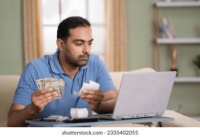 Indian man calculating monthly expenses from bills after salary while sitting on sofa at home - concept of Budget Planning, Money Management and Personal Finance - Powered by Shutterstock