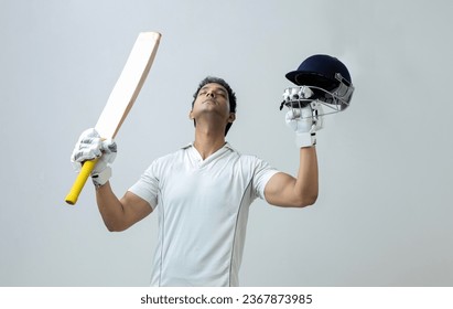 Indian man in cricket dress holding bat and helmet looking towards the sky celebrating century , cricket concept - Powered by Shutterstock