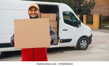 Indian Man Delivering Package. Holding Cardboard Box In Front Of The Van. High Quality Photo