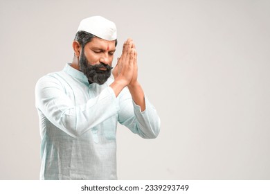 Indian man giving namaste or welcome gesture on white background.