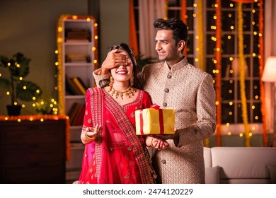 Indian man giving surprise gift to her wife in traditional wear on diwali or on anniversary - Powered by Shutterstock