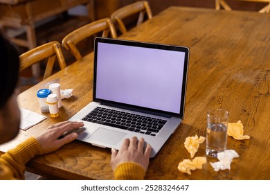 Indian man with medication on table making video call using laptop, copy space on screen at home. Medical services, communication, telemedicine and healthcare, unaltered. - Powered by Shutterstock