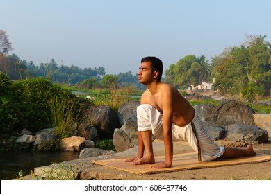 Indian Man Practicing Yoga Next To A River  In South India.