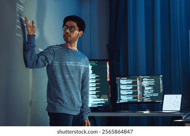 Indian man programmer standing in front of a screen with code projected  presentation the integration of technology and human expertise in software development