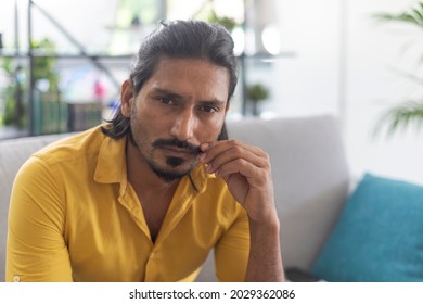 Indian Man Sitting On The Couch At Home And Adjusting His Moustache